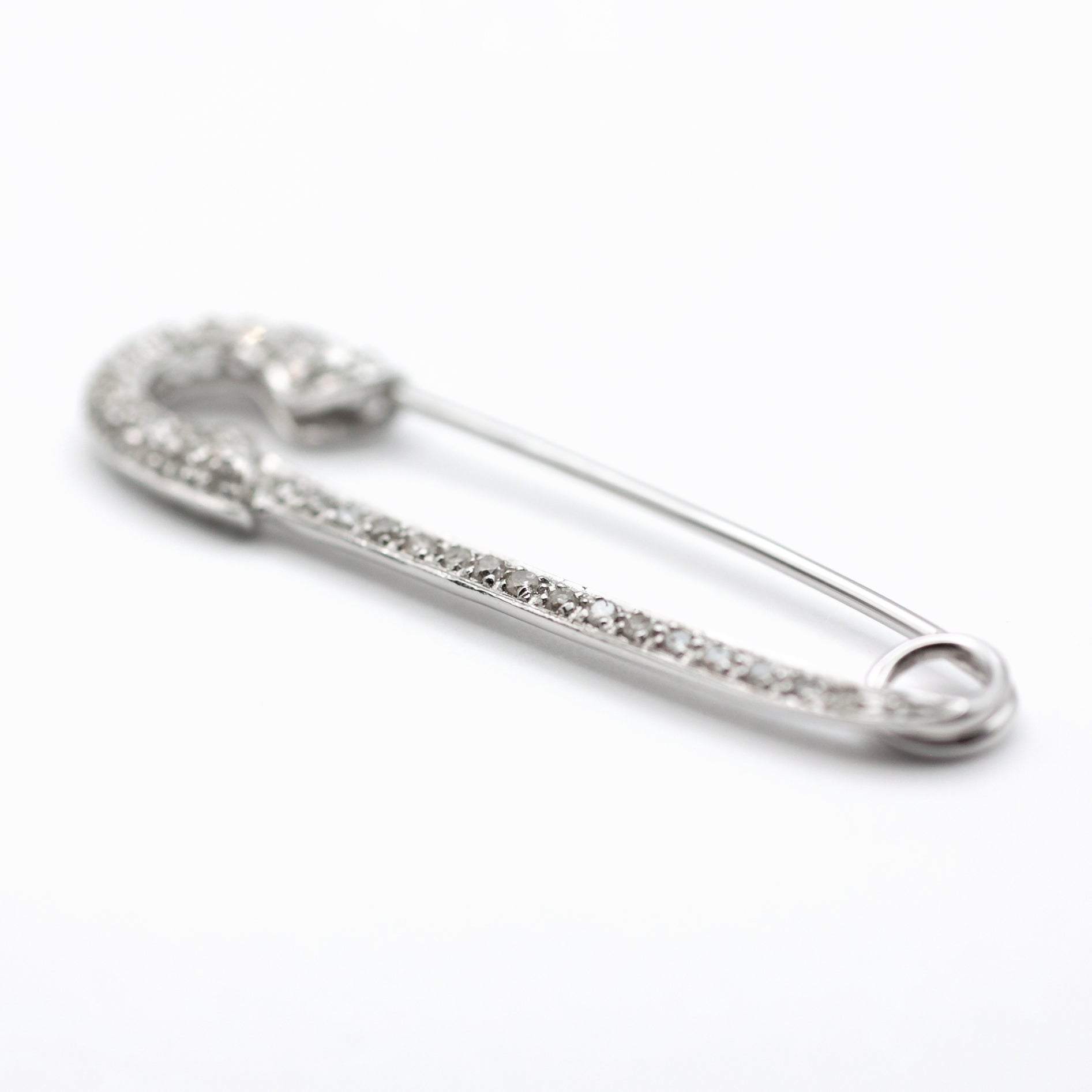 An antique 18ct white gold diamond safety pin brooch.